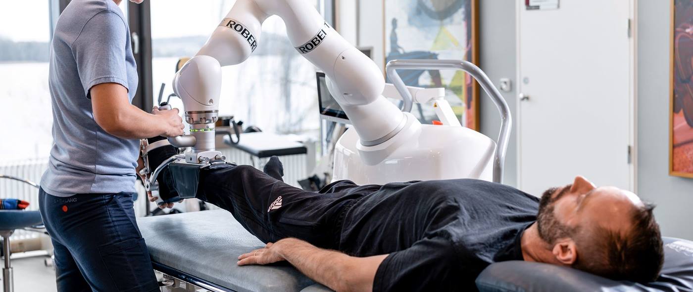 A therapist uses the LBR Med rehabilitation robot to provide movement therapy to a patient