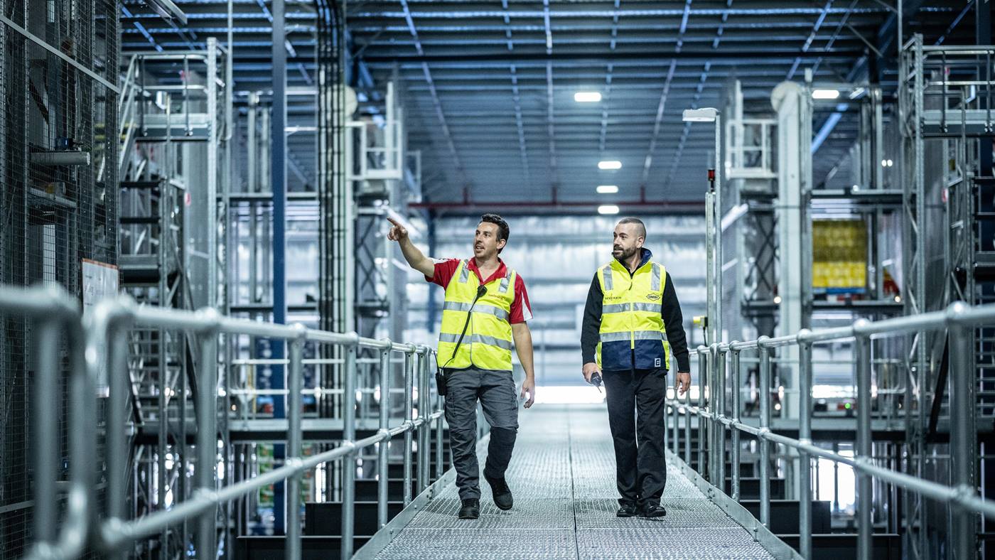Linfox/Swisslog PowerStore case study .Filmed at BevChain Auburn.(Accompanying video produced by We Know Video via Swisslog)..a person standing in front of a building with a metal fence